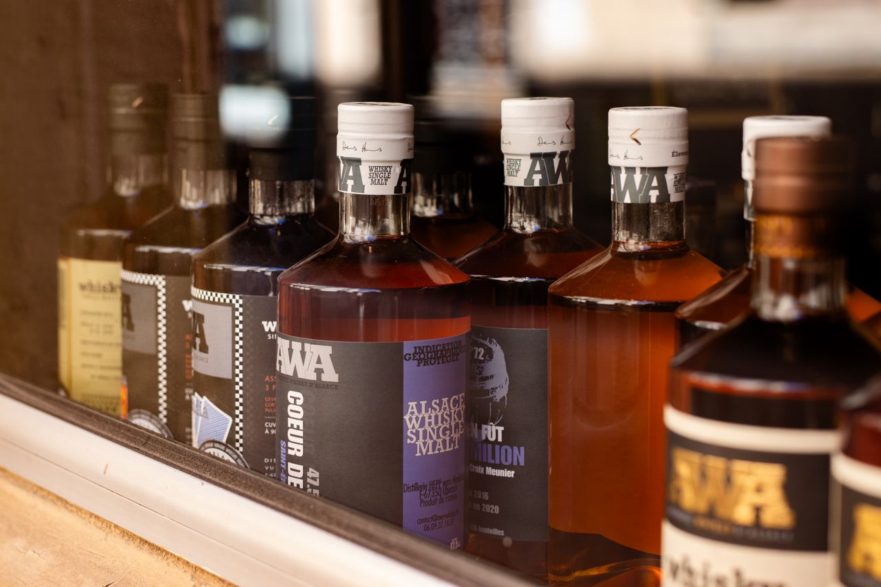 Close-up of Alsace whisky bottles displayed in a Colmar store window.