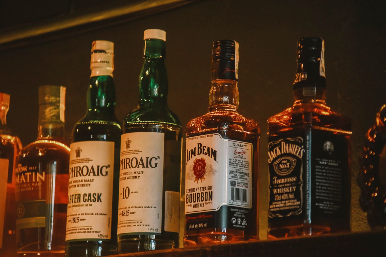 services-01 A selection of premium whiskey brands elegantly arranged on a dimly lit display shelf.